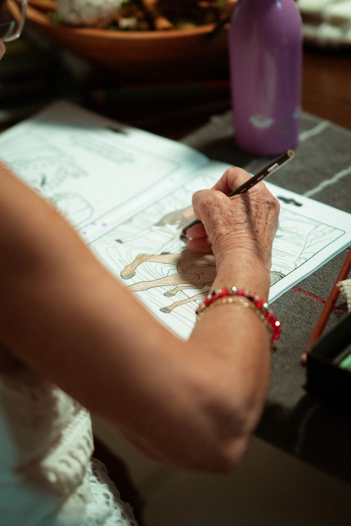 Elderly woman coloring in a book, showcasing relaxation and creativity.